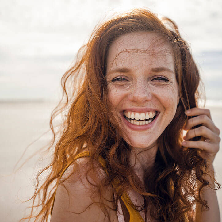 Natürliche, fröhliche Frau am Strand | Doppelherz