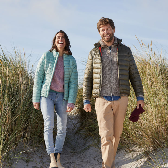 Lächelndes Paar geht durch Dünen am Strand