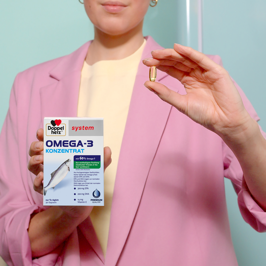 Frau hält Doppelherz system Omega-3-Konzentrat Produkt in der Hand