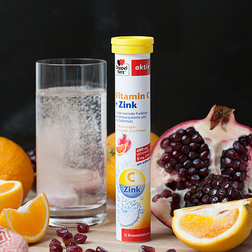 Doppelherz C+ Zink Brausetabletten mit Brausetablette in Glas und Granatäpfeln und Orangen